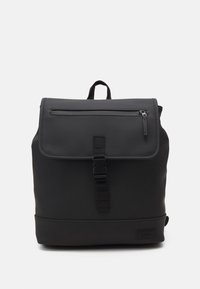 Zaino nero con texture opaca, tasca frontale con zip, pattina pieghevole e chiusura con fibbia regolabile. Etichetta con logo sulla base.