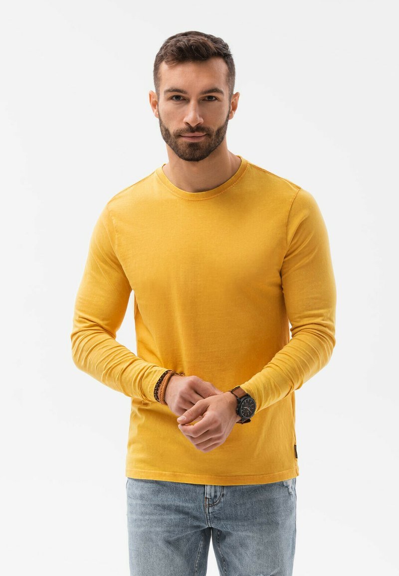 Langemouwige gele katoenen t-shirt met een ronde halsline, gecombineerd met lichtblauwe denim jeans, die een casual pasvorm en een zachte structuur laten zien.