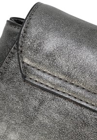 Metallisch grauer Lederstiefel mit strukturierter Oberfläche, versehen mit einer genähten Naht und einem geschwungenen Kragenrand. Glatte Oberfläche mit leichtem Glanz.