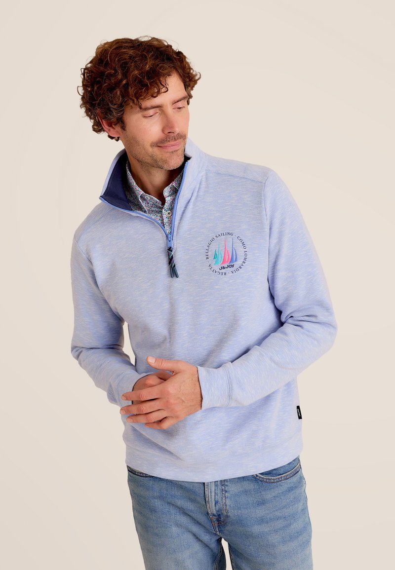 Lichtblauw, kwart-rits pullover gemaakt van zachte stof, met marineblauwe kraagaccenten en een kleurrafische zeilbootafbeelding op de borst.