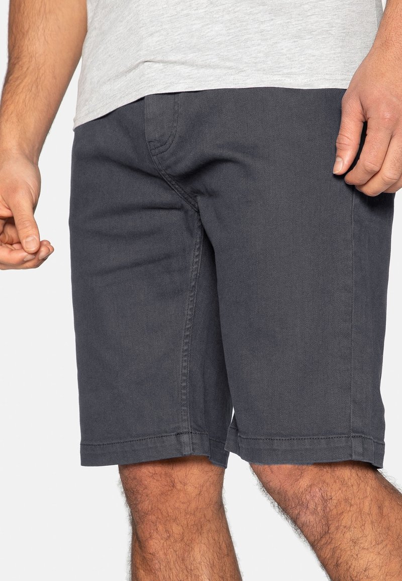 Shorts gris foncé en coton doux avec une coupe classique, dotés de poches latérales et de coutures visibles sur l'ourlet, offrant une coupe décontractée.