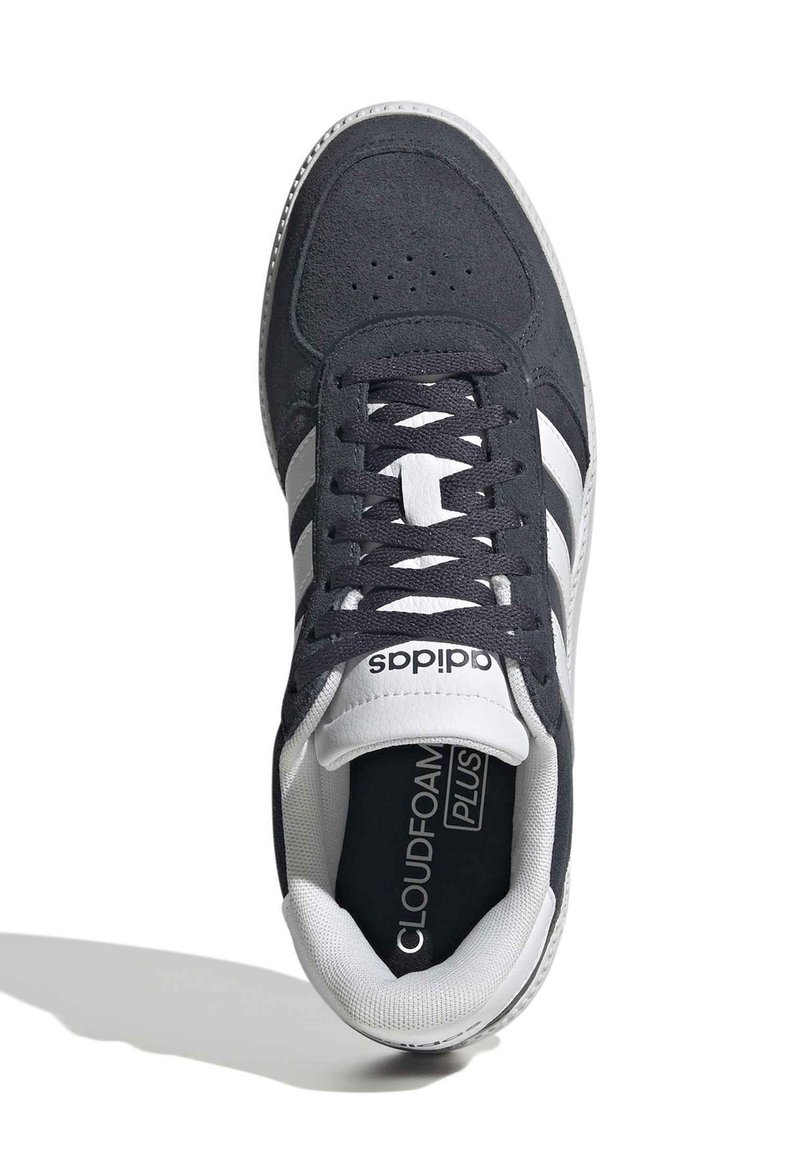 Zapatilla deportiva gris oscuro con diseño de tres rayas blancas. Presenta una parte superior de ante, cierre de cordones, cuello acolchado y plantilla Cloudfoam.