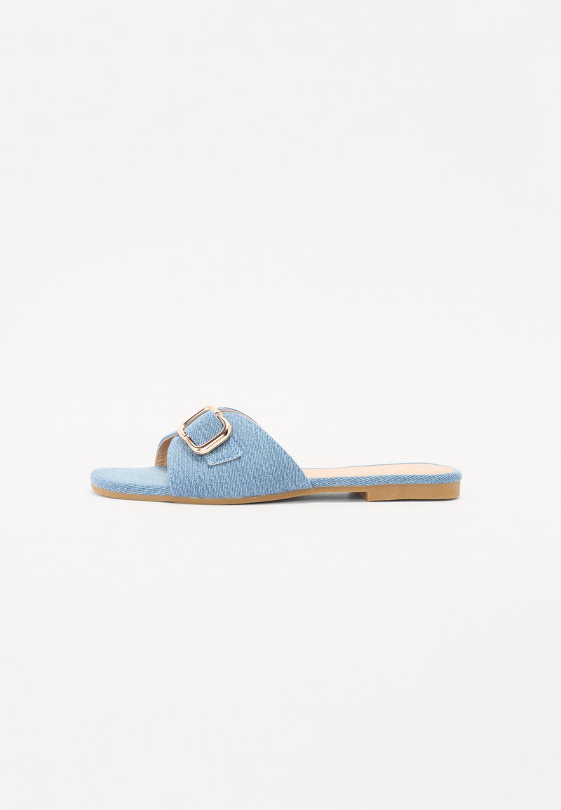 Blå denim skyvesandal med en bred stropp, med en gulldtonet firkantet spenne og en flat brun såle. Enkel design, uformell stil.