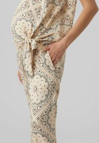 Beige mönstrade gravidbyxor med paisleymönster, med knytmidja, sidoficka och slät tygtextur.