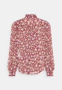 Blouse à fleurs rouges en tissu léger et transparent. Caractéristiques : col montant, manches longues bouffantes et dos boutonné avec un design froncé.