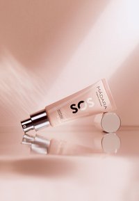 Crema idratante MÁDARA SOS Eye Revive in un tubo rosa con cappuccio a pompa argentato. Texture liscia e design moderno, che riflette delicatamente la luce.
