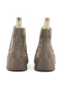Sneakers alte in suede grigio chiaro con borchie metalliche decorative, suola in gomma marrone e linguetta con logo a contrasto sul retro.