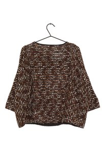 Top lavorato a maglia nero e marrone con vestibilità ampia, maniche larghe, motivo zigzag testurizzato e scollo nero uniforme, esposto su un appendiabiti.