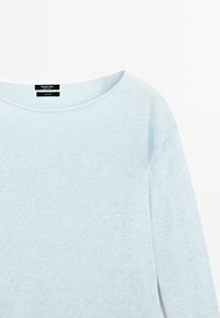 Pull en lin bleu clair à manches longues avec encolure bateau et étiquette noire visible à l'intérieur du col.