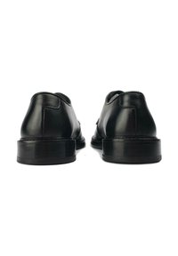 Black leather shoes with low heels, smooth texture, rounded toes, and visible stitching detail on the back.