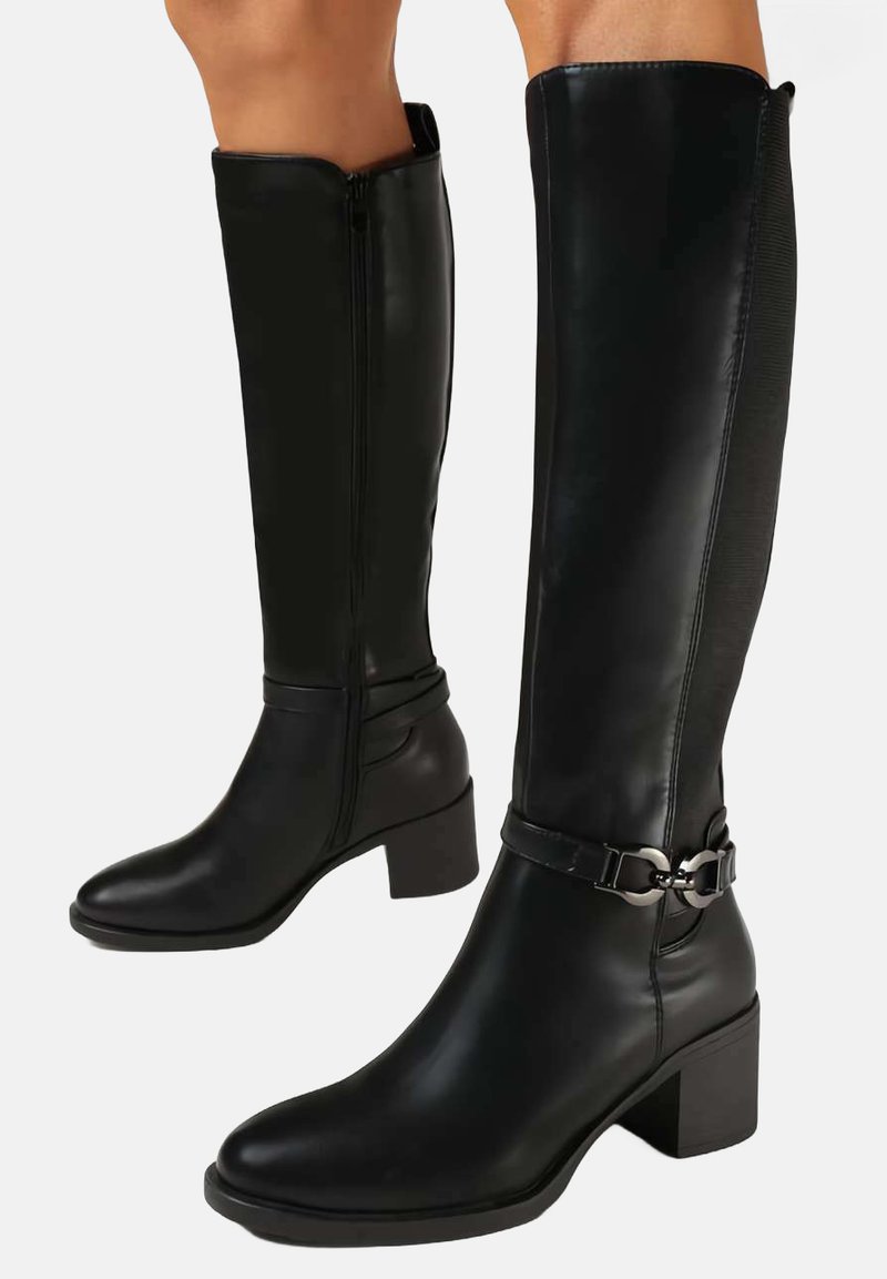 Bottes en cuir noir jusqu'au genou avec un talon carré, fermeture éclair et accent de boucle à la cheville. Texture lisse, silhouette structurée.