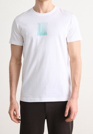 Witte katoenen T-shirt met een mintgroen abstract grafisch ontwerp, ronde hals en korte mouwen. Eenvoudig, minimalistisch ontwerp.