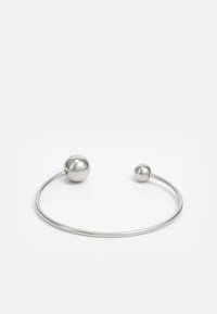 Pulsera de pulsera de metal plateado con un diseño suave y curvado, y dos acentos esféricos en cada extremo. Minimalista y elegante.