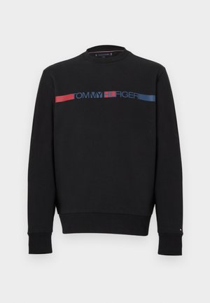 Felpa nera con scollo tondo, maniche lunghe e polsini a costine. Presenta una banda orizzontale con logo in rosso e blu sul petto.