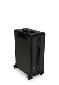 Kemény tokos bőrönd sötétbarna kutyanyelv mintával, fekete részletekkel, egy felső fogantyúval és négy kerékkel a könnyű mozgathatóság érdekében.