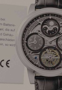 Mechanische Uhr mit silbernem Gehäuse, schwarzem Lederarmband und mehreren Ziffernblättern. Sichtbare Zahnräder und aufwendige Details verbessern die Sichtbarkeit der Zeit.