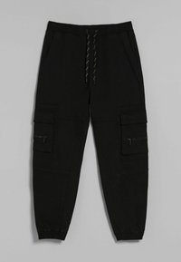 Svarta cargobyxor med elastisk midja och snörning. Har flera fickor, inklusive dragkedjefickor och luckor. Avsmalnande ben.