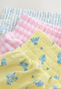 Quattro campioni di tessuto in colori pastello: a righe blu e bianche, a quadretti rosa, rosa chiaro e giallo con motivi floreali blu. Tessuti con texture e arricciati.