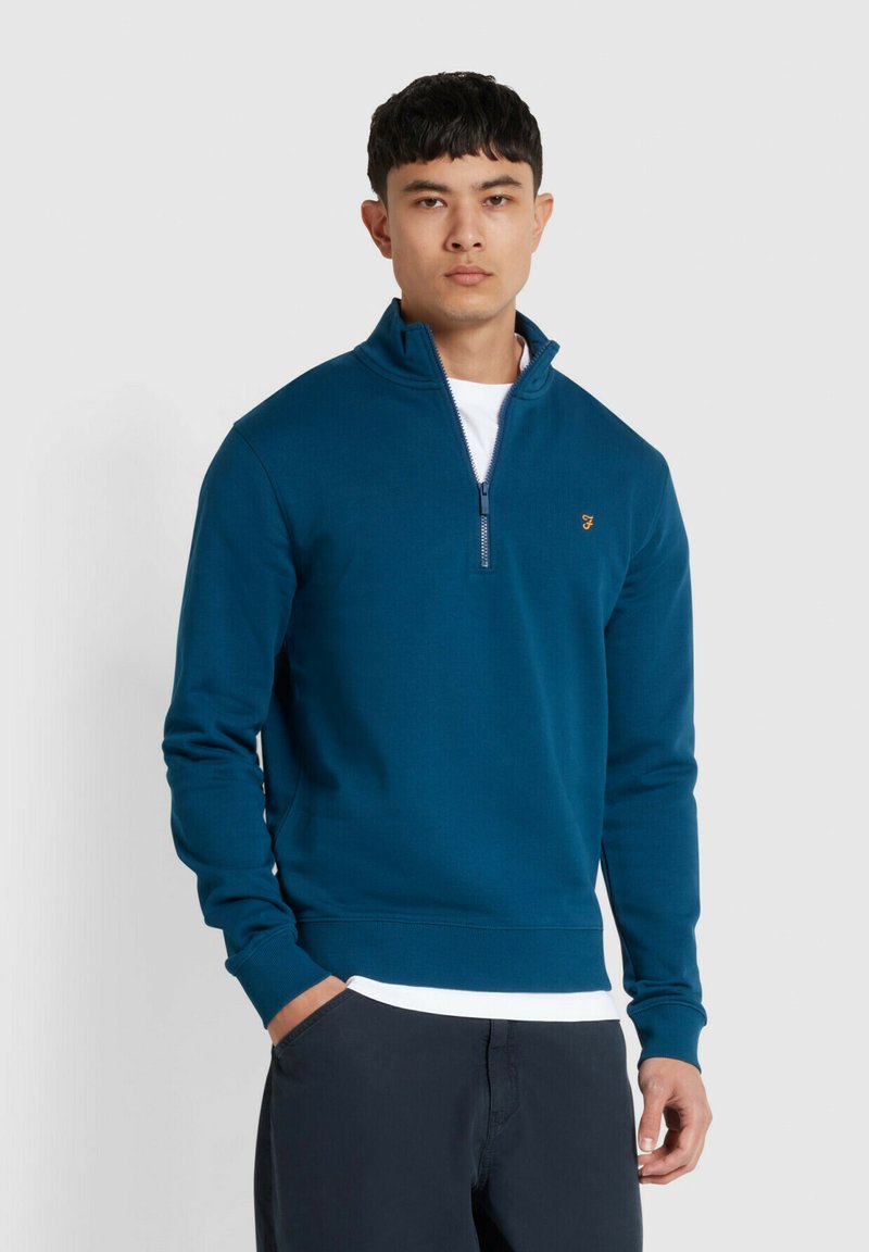 Türkisfarbener Sweatshirt mit Reißverschluss am Kragen, tailliertem Schnitt, langen Ärmeln und gerippten Bündchen. Mit kleinem, auf der Brust gesticktem Logo.