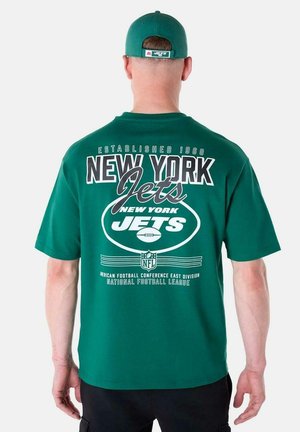 Camiseta verde con "NEW YORK JETS" en texto blanco en negrita, gráficos de fútbol y el año de establecimiento 1960; mangas cortas y cuello redondo.