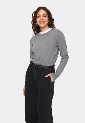 Grå långärmad tröja med rundad halsringning, i kombination med högmidjade svarta jeans som har sidfickor och ett svart texturerat bälte.