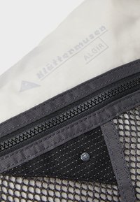 Graues Netzgewebe mit einem weißen Innenfutter, ausgestattet mit einem Reißverschluss, einem Logo und einem Knopfakzent. Strukturierte Oberfläche mit einem Rautenmuster.