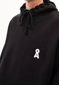 Felpa nera con cappuccio regolabile, caratterizzata da un logo ricamato bianco sul petto. Realizzata in un morbido tessuto testurizzato.