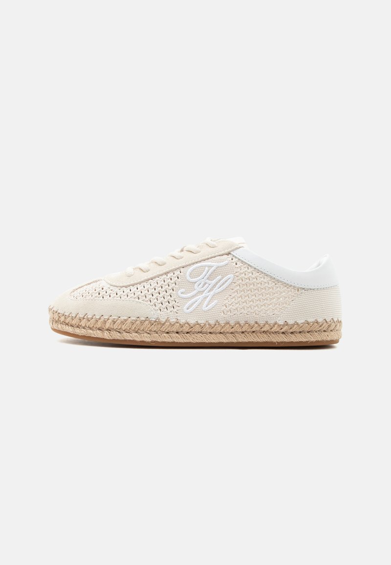 Baskets décontractées beige avec texture tissée, lacets blancs, logo "TH" blanc brodé sur le côté, et semelle en jute tressé sur fond blanc.