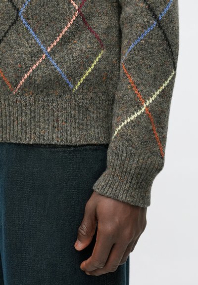 Sötétszürke gyapjúból készült kötött pulóver színes rombuszmintákkal rózsaszín, kék, narancs és sárga színekben. Bordázott mandzsetták és szegély. Sötét farmerral viselve.