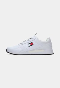 Biele tenisky Tommy Jeans s viazaním vpredu, čierno-červenobiely logotyp značky po strane, polstrovaná podrážka a čierna podrážka, zobrazené z pravej strany.