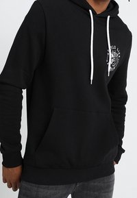 Black hoodie made of soft fabric, featuring a kangaroo pocket, white drawstrings, and a graphic print on the chest.