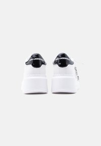 Λευκά αθλητικά παπούτσια με γυαλιστερή μαύρη λεπτομέρεια στη φτέρνα, με υφή στη σόλα και το λογότυπο «KARL LAGERFELD» στο πίσω μέρος.