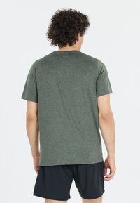 Camiseta verde de manga corta hecha de una tela suave, con un escote redondo y un corte relajado. La vista posterior muestra una textura suave y un diseño simple.
