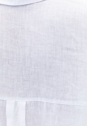 Tessuto di lino bianco con una trama sottile, caratterizzato da una linea di cucitura dritta e un piccolo dettaglio di piega nella parte inferiore.