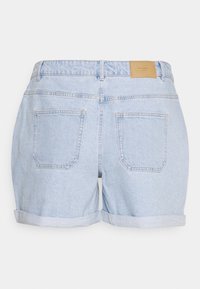 Pantalones cortos de mezclilla azul claro con puños enrollados, que cuentan con dos bolsillos traseros y una etiqueta de cuero marrón en la cinturilla.