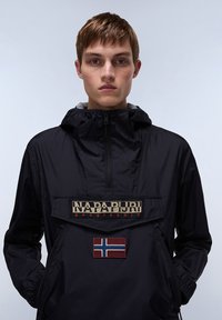Zwarte lichtgewicht anorakjas met een ritskraag, capuchon, opvallend logo en Noorse vlagpatch op de voorzak.