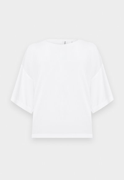Λευκό μπλουζάκι με κοντά μανίκια, φαρδιά μανίκια και στρογγυλή λαιμόκοψη, σε απλό φωτεινό φόντο.