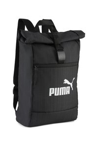 Sac à dos noir à rabat enroulable en tissu texturé, doté d'une poche zippée à l'avant et d'un logo blanc. Sangles ajustables et fermeture à boucle robuste.