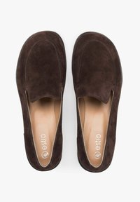 Brown suede slip-on shoes with a rounded toe and subtle cutout detail. Soft interior lining and flat black outsole. Brand name "estro" visible inside.