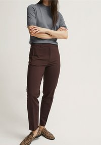 Grå t-shirt med kort ärm i kombination med mörk vinröda slim-fit byxor och bruna loafers med ormskinnsmönster. Mjukt tyg med en figurnära design och rena linjer.