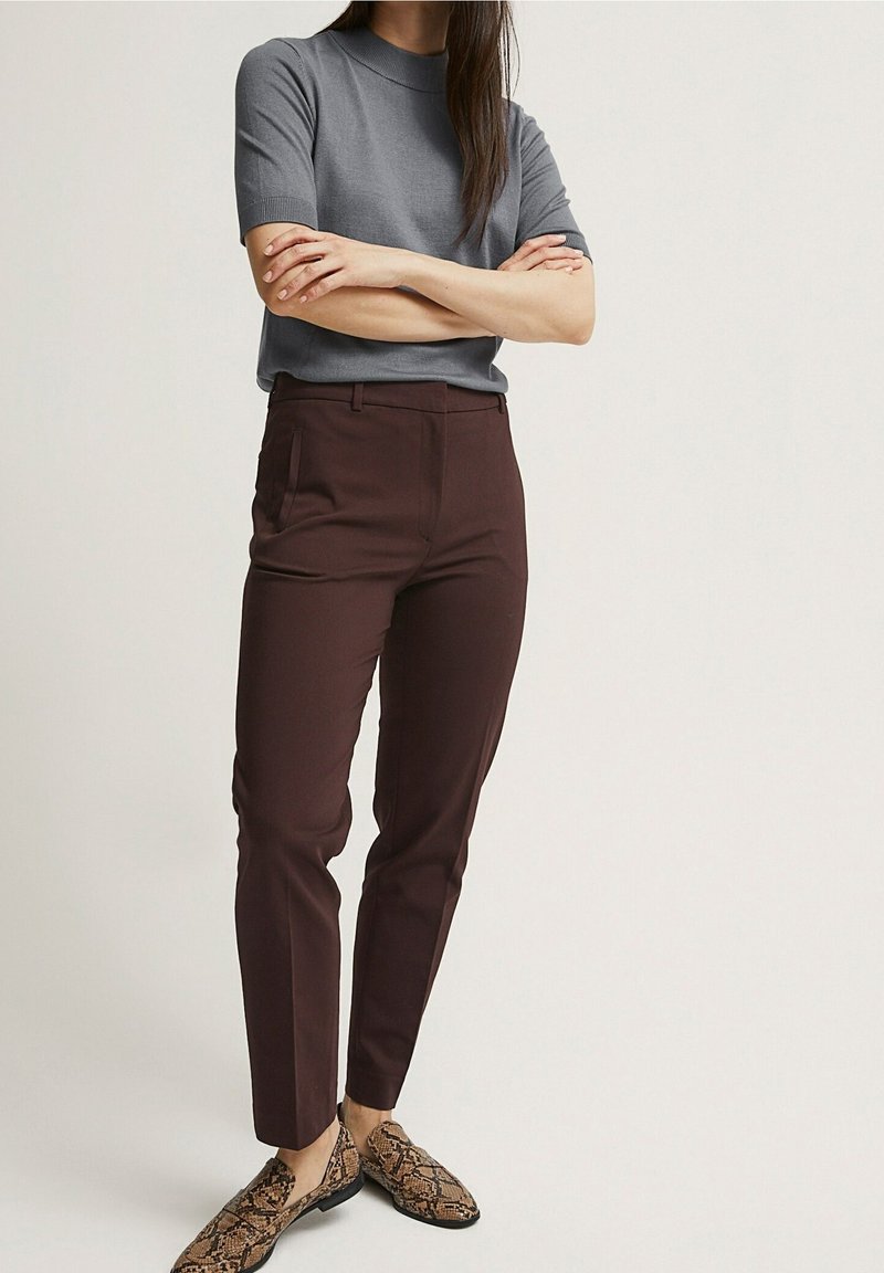 Grå t-shirt med kort ärm i kombination med mörk vinröda slim-fit byxor och bruna loafers med ormskinnsmönster. Mjukt tyg med en figurnära design och rena linjer.