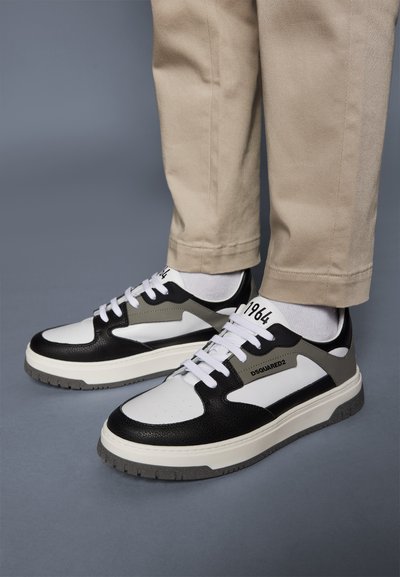 Sneaker in bianco e nero con accenti grigi. Presenta una parte superiore in pelle texturizzata, una punta perforata e lacci bianchi. Suola in gomma.