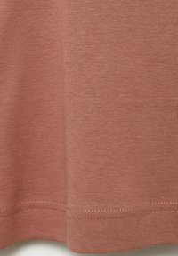 Textiele T-shirt in stofroze kleur, met een gladde katoentextuur, rechte zoom en eenvoudige gestikte details langs de rand.