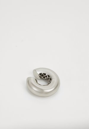 Objet sculptural en métal en forme lisse et courbée avec une finition argentée brillante, présentant un design en treillis ouvert et complexe à l'intérieur.