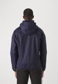 Mørkeblå letvægtsjakke med hætte, elastiske manchetter og bund, samt en glat tekstur. Har et enkelt, funktionelt design.