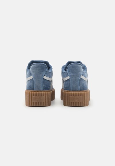 Baskets en suede bleu avec une semelle en caoutchouc brun striée, présentant des accents bleu clair et un col rembourré pour le confort.