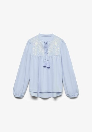 Lyseblå bluse med lange ermer og rund krage, blomstrete broderi på brystet, innsvingt sal, duskebånd og elastiske mansjetter.