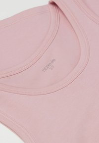 Jasnoróżowa bluzka bez rękawów, wykonana z miękkiego materiału, z okrągłym dekoltem i widocznym logo marki na środku. Gładka tekstura i elastyczny fason.