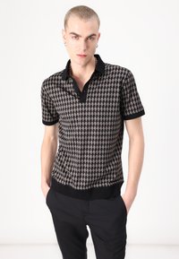 Mustmust ja beežikirjaline polo-särk, millel on kaelus, lühikesed varrukad ja ühtlane must serv. Sile tekstuur koos geomeetriliste printidega.