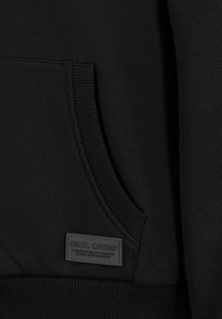 Schwarzes Sweatshirt mit einer vorderen Kängurutasche, gerippten Bündchen und Saum sowie einem strukturierten Markenschild mit eingeprägtem Schriftzug. Glatter Stofftextur.